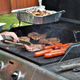Hands using tongs to flip meat on a backyard grill